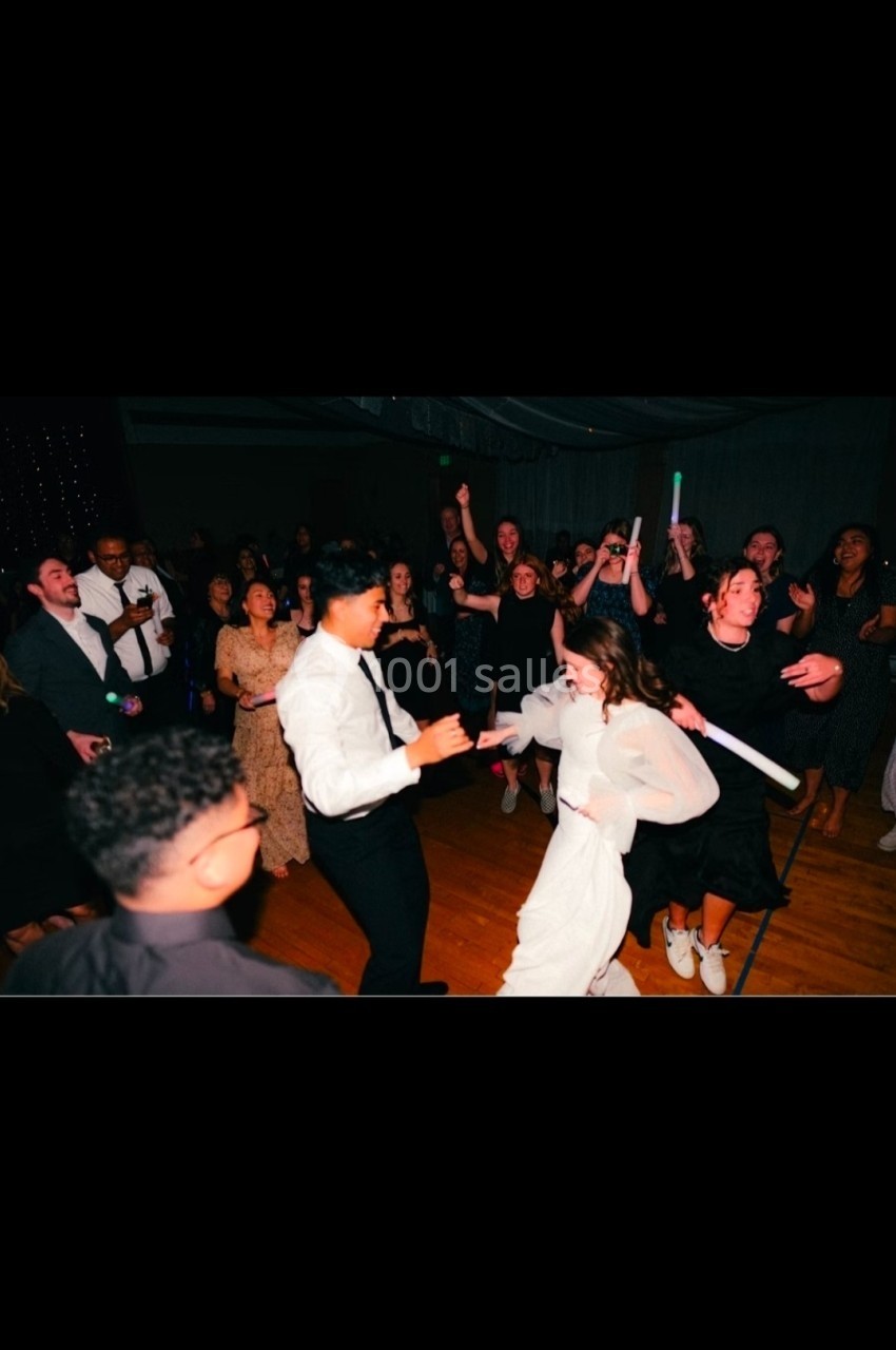 Des personnes dansent et s'amusent sur une piste de danse éclairée, entourées d'une foule festive.