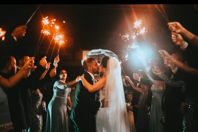 Miniature DJ Melun (Seine-et-Marne) - Dj Urya #9 Un couple s'embrasse sous une arche, entouré d'invités tenant des cierges magiques allumés dans l'obscurité.