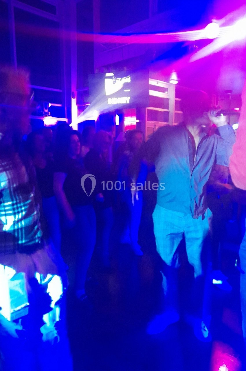 Groupe de personnes dansant dans une ambiance lumineuse et colorée, avec des néons et des ombres en arrière-plan.