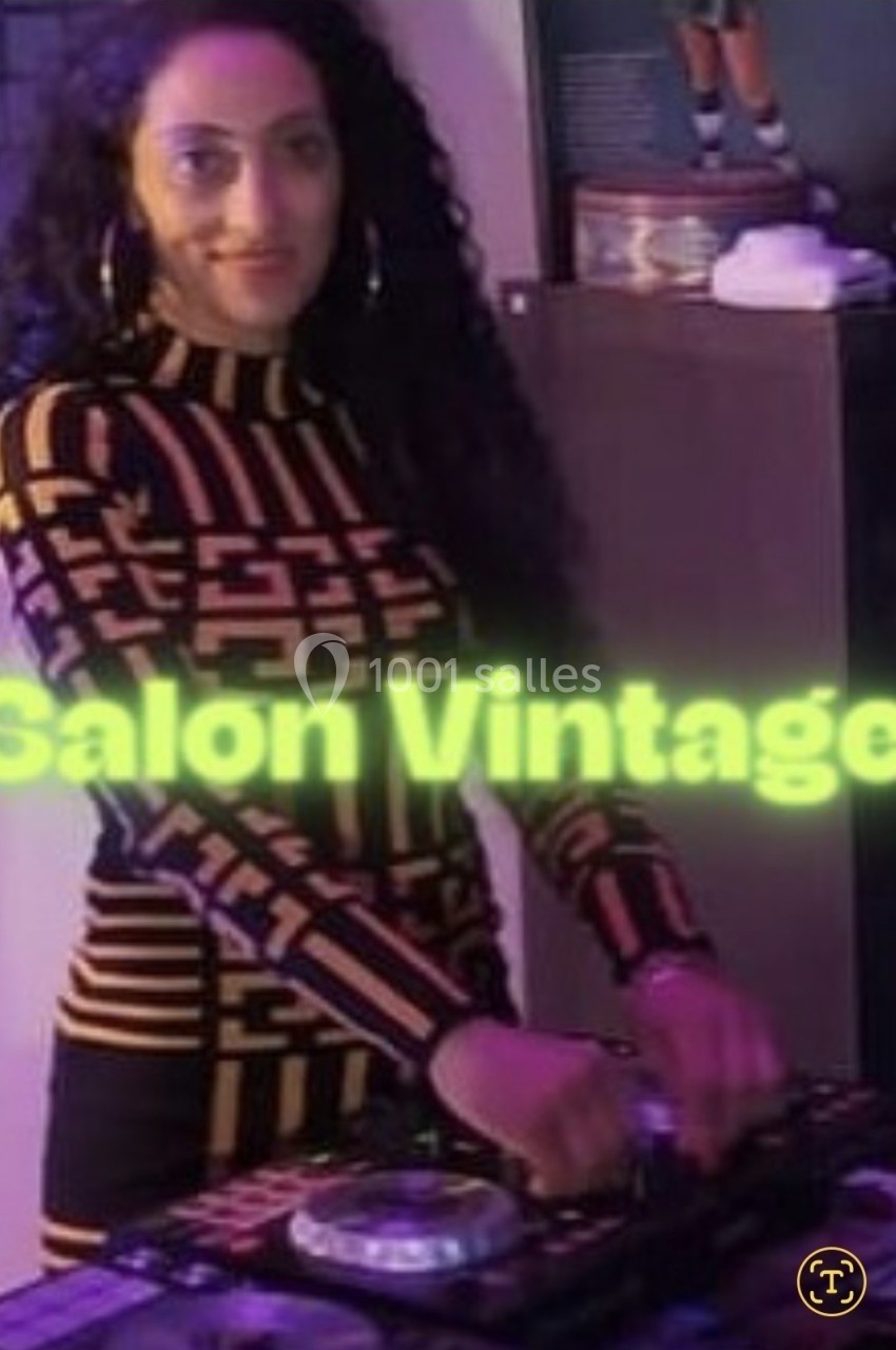 Femme aux cheveux bouclés mixant de la musique sur une table de mixage dans un espace éclairé par une lumière colorée.