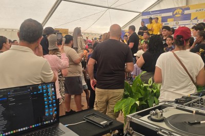 Miniature DJ Le Mée-sur-Seine (Seine-et-Marne) - Dj Urya #14 Une DJ en robe verte mixe de la musique sur une table de mixage dans un décor lumineux avec des fleurs de cerisier.