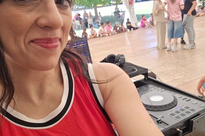 Miniature DJ Le Mée-sur-Seine (Seine-et-Marne) - Dj Urya #15 Une DJ en robe verte mixe de la musique sur une table de mixage dans un décor lumineux avec des fleurs de cerisier.