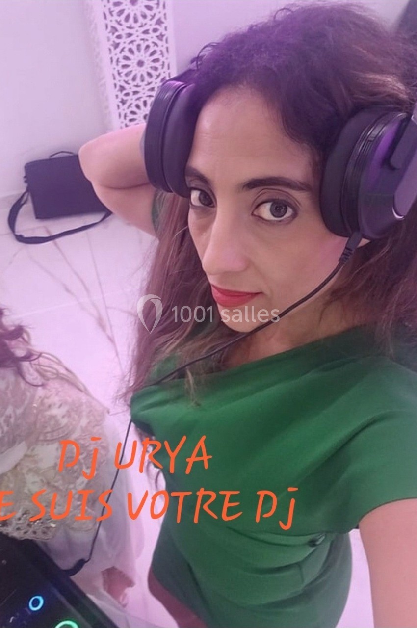 Femme portant un casque audio, debout près d'un équipement de DJ dans un espace intérieur lumineux.
