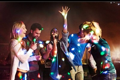 Femme devant une table de mixage avec ordinateurs, dans une salle où se déroule un événement sportif ou culturel.