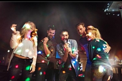 Femme devant une table de mixage avec ordinateurs, dans une salle où se déroule un événement sportif ou culturel.