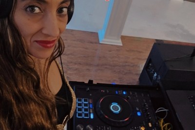 Femme devant une table de mixage avec ordinateurs, dans une salle où se déroule un événement sportif ou culturel.