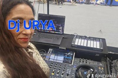 Femme devant une table de mixage avec ordinateurs, dans une salle où se déroule un événement sportif ou culturel.