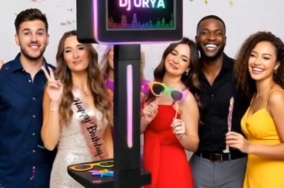 Un groupe de cinq personnes souriantes posant autour d'une borne photo lumineuse, avec des accessoires festifs.