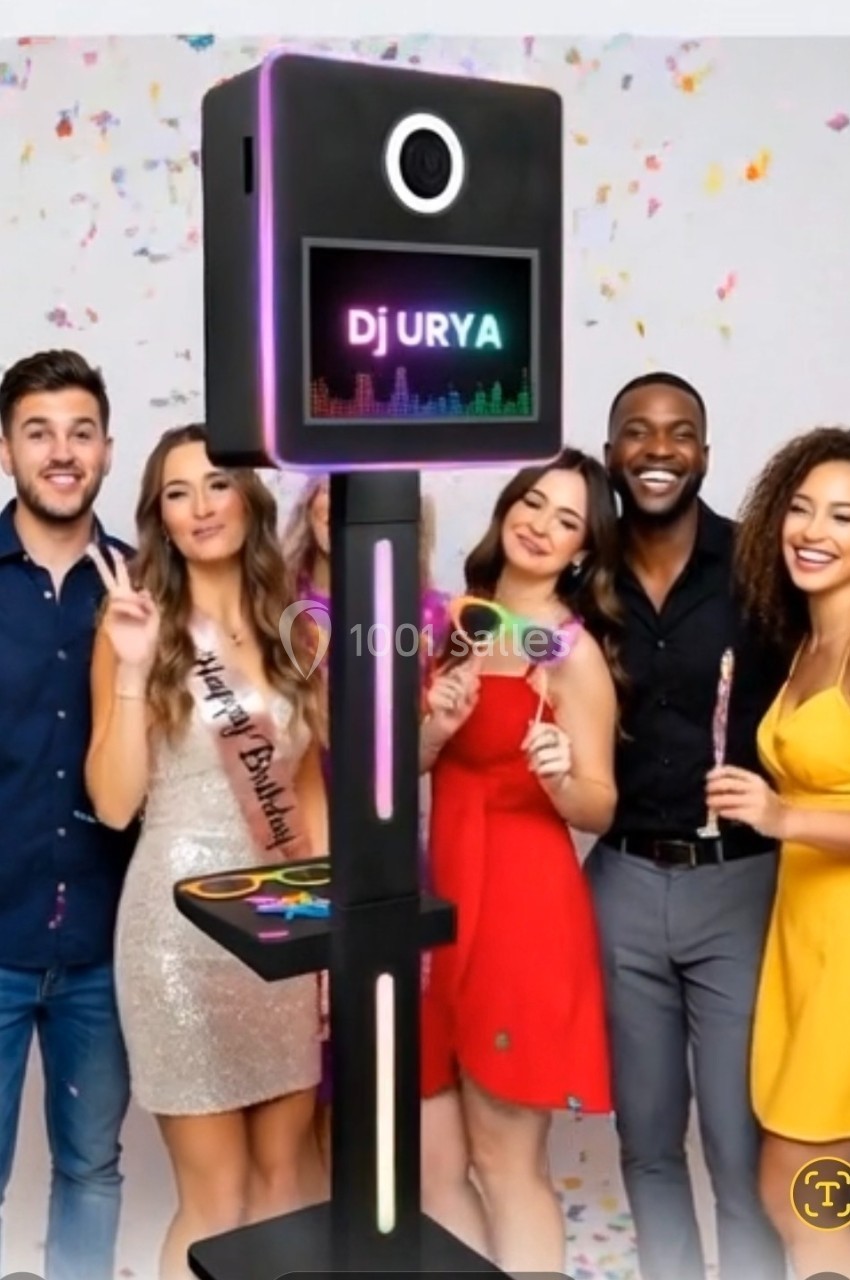 Un groupe de cinq personnes souriantes posant autour d'une borne photo lumineuse, avec des accessoires festifs.