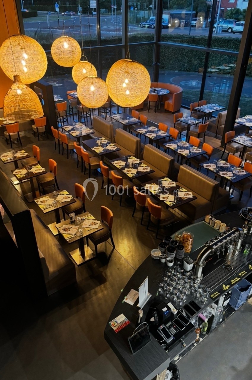 Vue d'ensemble d'un restaurant moderne avec tables dressées, grandes baies vitrées et luminaires suspendus en rotin.