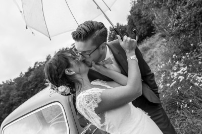 Silhouettes d'un couple s'embrassant sous une arche ornée de feuillage, en contre-jour.