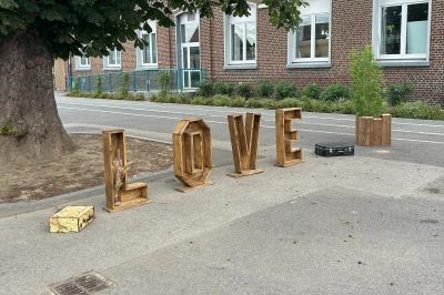 Trois valises vintage empilées, en cuir et tissu, posées sur une surface en extérieur avec de l'herbe en arrière-plan.