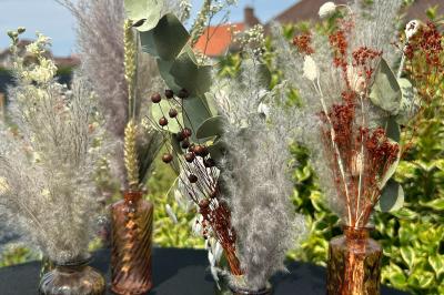 Trois valises vintage empilées, en cuir et tissu, posées sur une surface en extérieur avec de l'herbe en arrière-plan.