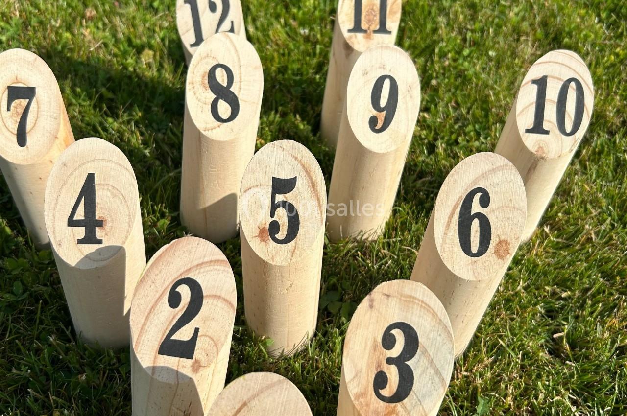 Quilles en bois numérotées disposées sur une pelouse, utilisées pour un jeu en extérieur.