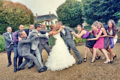 Miniature Victor Podgorski Photographe #5 Un couple en tenue de mariage s'embrasse dans un champ de blé, tenant des ballons colorés sous un ciel bleu.