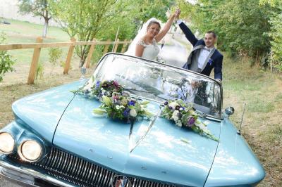 Miniature Victor Podgorski Photographe #13 Un couple en tenue de mariage s'embrasse dans un champ de blé, tenant des ballons colorés sous un ciel bleu.