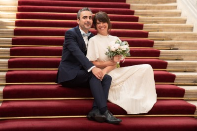 Voiture ancienne décapotable décorée de fleurs pour une cérémonie, stationnée sur une rue pavée.