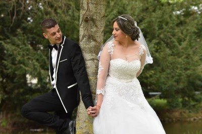 Voiture ancienne décapotable décorée de fleurs pour une cérémonie, stationnée sur une rue pavée.
