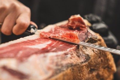 Tentacules de poulpe grillés dans une poêle chaude, manipulés avec une pince en cuisine.