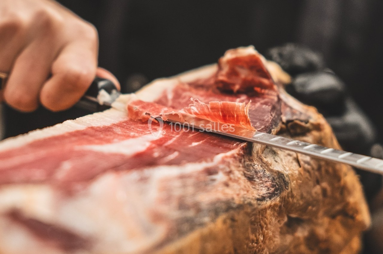 Tranche fine de jambon cru découpée à la main sur un morceau de jambon entier.