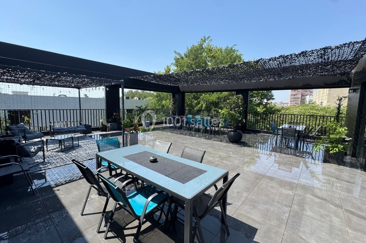 Terrasse spacieuse avec tables, chaises et pergola, entourée de verdure et baignée de lumière naturelle.