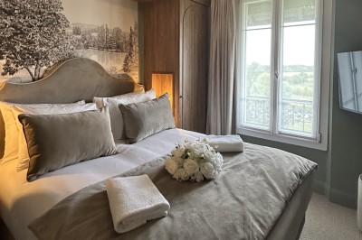 Salle de réunion lumineuse avec table en bois, chaises rembourrées, bouteilles d'eau et grandes fenêtres avec rideaux…