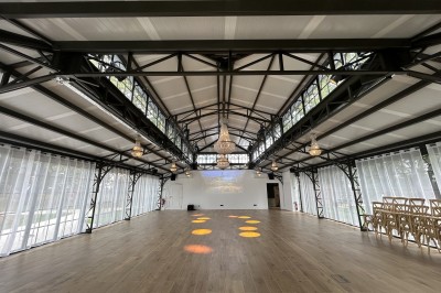 Salle de réunion lumineuse avec table en bois, chaises rembourrées, bouteilles d'eau et grandes fenêtres avec rideaux…