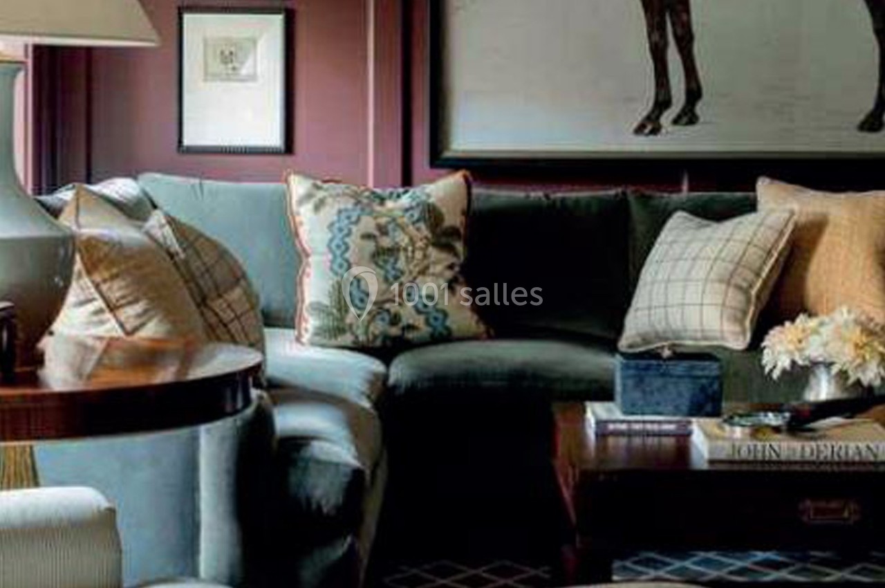 Canapé d'angle vert avec coussins décoratifs, table basse en bois et lampe dans un salon à la décoration classique.