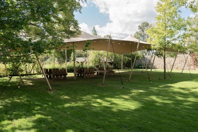 Salle de réunion lumineuse avec table en bois, chaises rembourrées, bouteilles d'eau et grandes fenêtres avec rideaux…