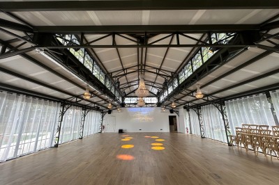 Salle de réunion lumineuse avec table en bois, chaises rembourrées, bouteilles d'eau et grandes fenêtres avec rideaux…