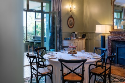 Salle de réunion lumineuse avec table en bois, chaises rembourrées, bouteilles d'eau et grandes fenêtres avec rideaux…