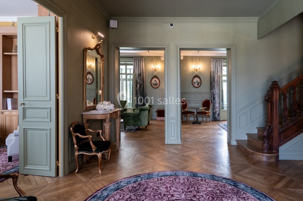 Intérieur d'une maison élégante avec parquet, meubles anciens, miroirs et escaliers en bois.