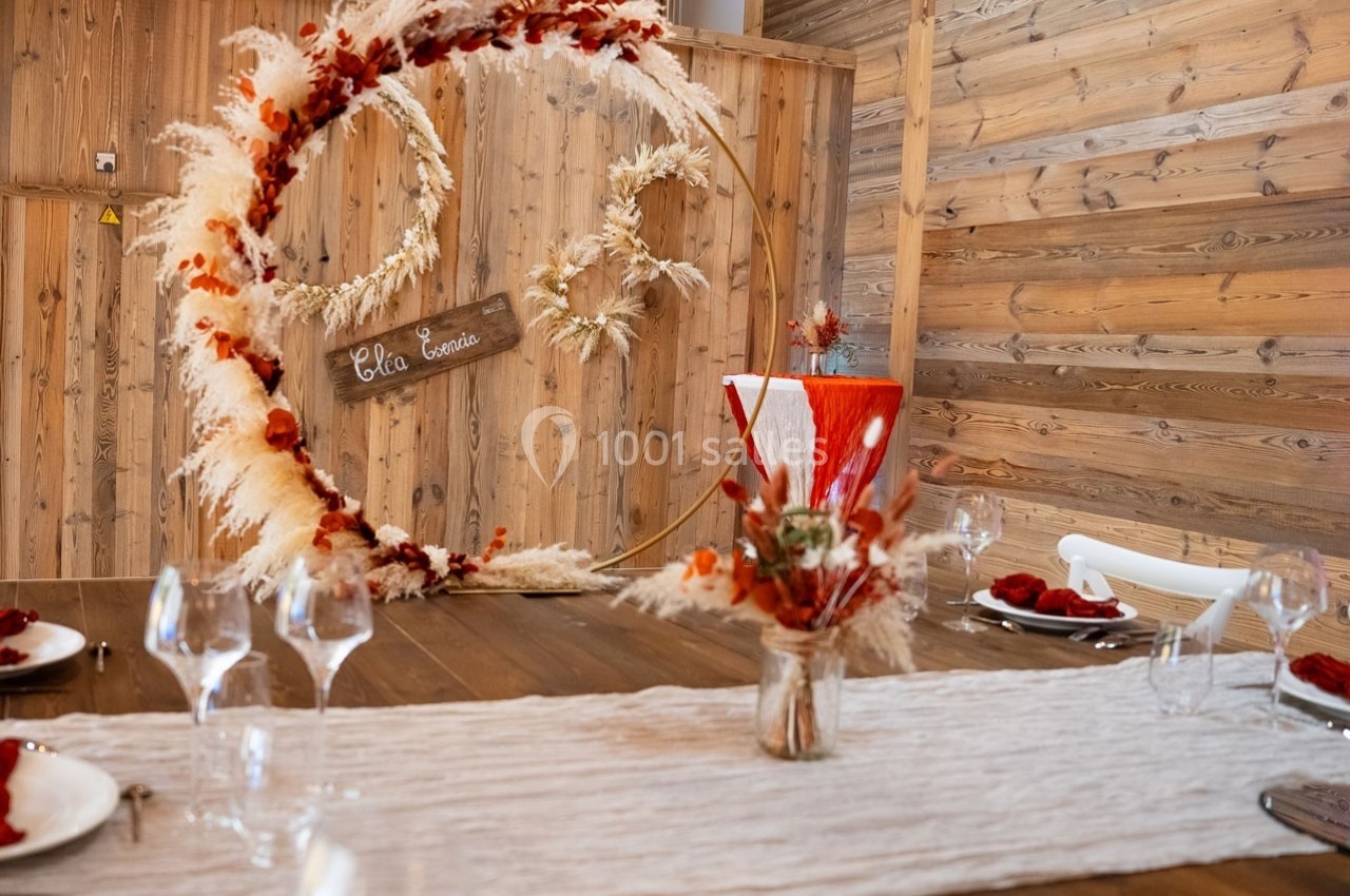 Décoration de table en bois avec des éléments floraux séchés, un centre de table circulaire et des verres disposés.