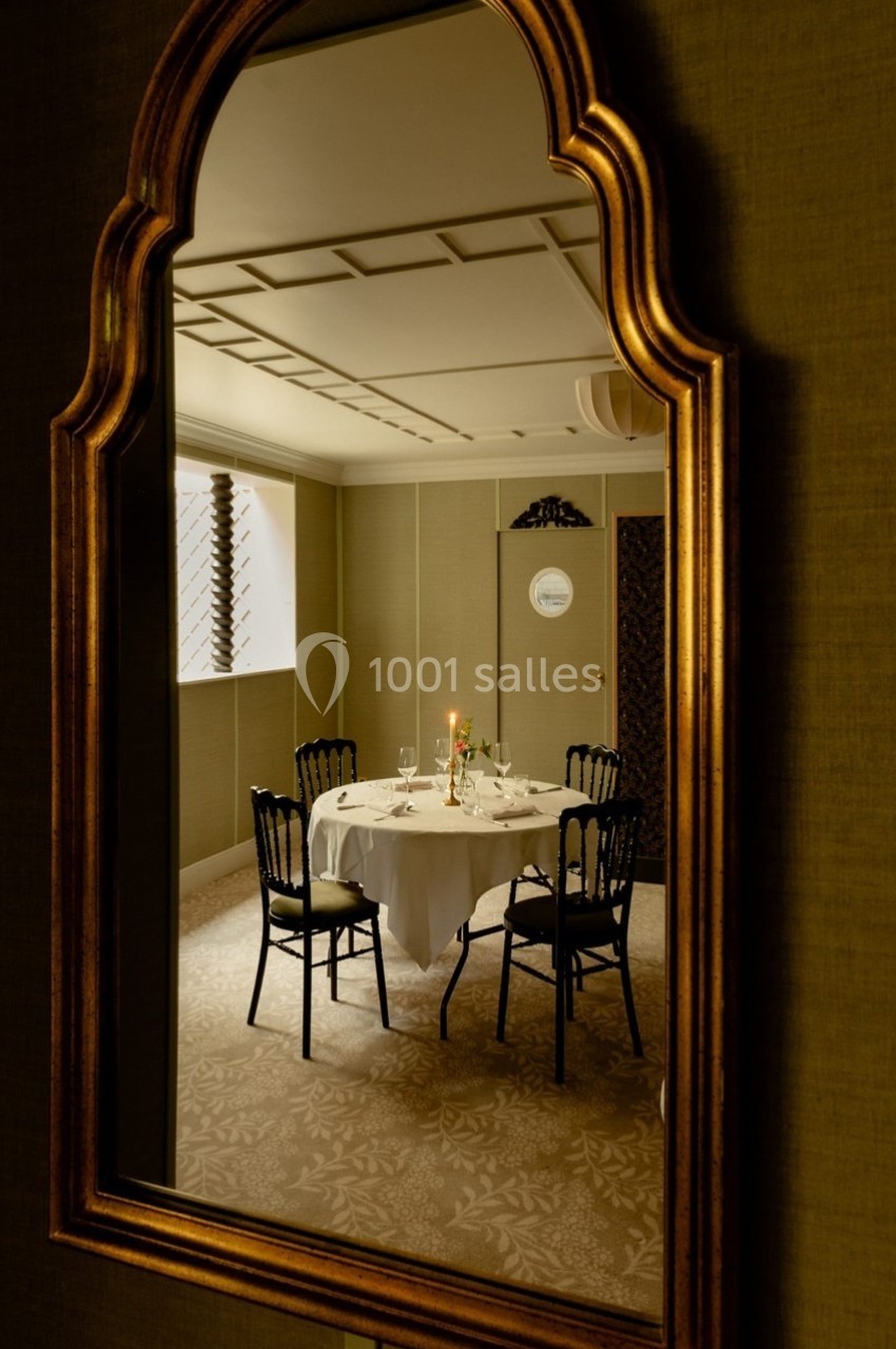 Reflet d'une table dressée pour deux dans un miroir doré, avec un intérieur élégant et tamisé en arrière-plan.