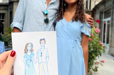 Illustration d'une femme souriante en tenue décontractée, posée sur une table en bois avec des coquillages en arrière-plan.