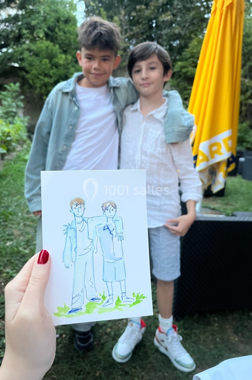 Deux enfants posant ensemble dans un jardin, avec un dessin les représentant tenu au premier plan.