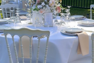 Table élégamment dressée avec nappes blanches, vaisselle raffinée, bougies roses et décoration florale assortie.