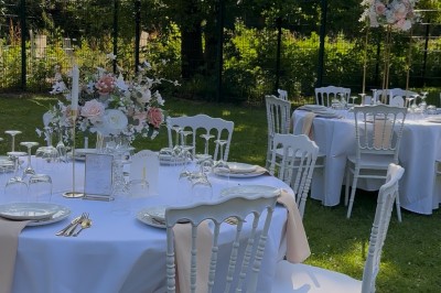 Table élégamment dressée avec nappes blanches, vaisselle raffinée, bougies roses et décoration florale assortie.