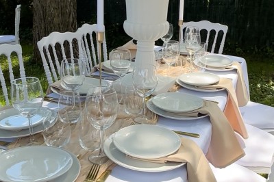 Table élégamment dressée avec nappes blanches, vaisselle raffinée, bougies roses et décoration florale assortie.