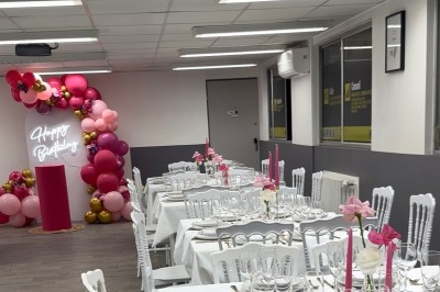Table élégamment dressée avec nappes blanches, vaisselle raffinée, bougies roses et décoration florale assortie.