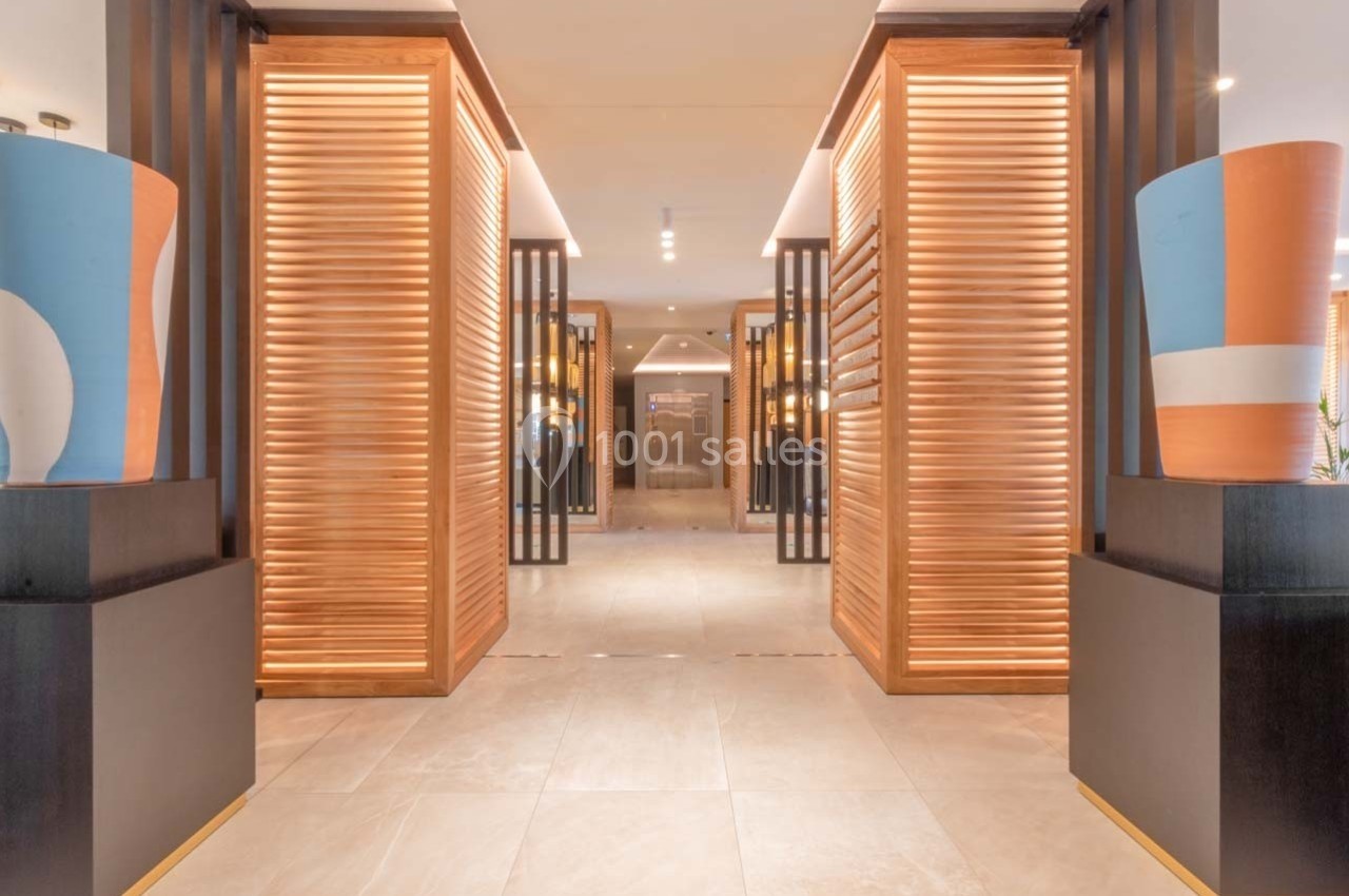 Vue d'un couloir moderne avec des panneaux en bois ajourés, éclairage chaleureux et décorations colorées.