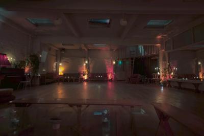 Miniature Location salle Paris 17 (Paris) - Loft Lechapelais #10 Salle spacieuse avec éclairage tamisé orange, murs en pierre, bancs en bois et décorations végétales.