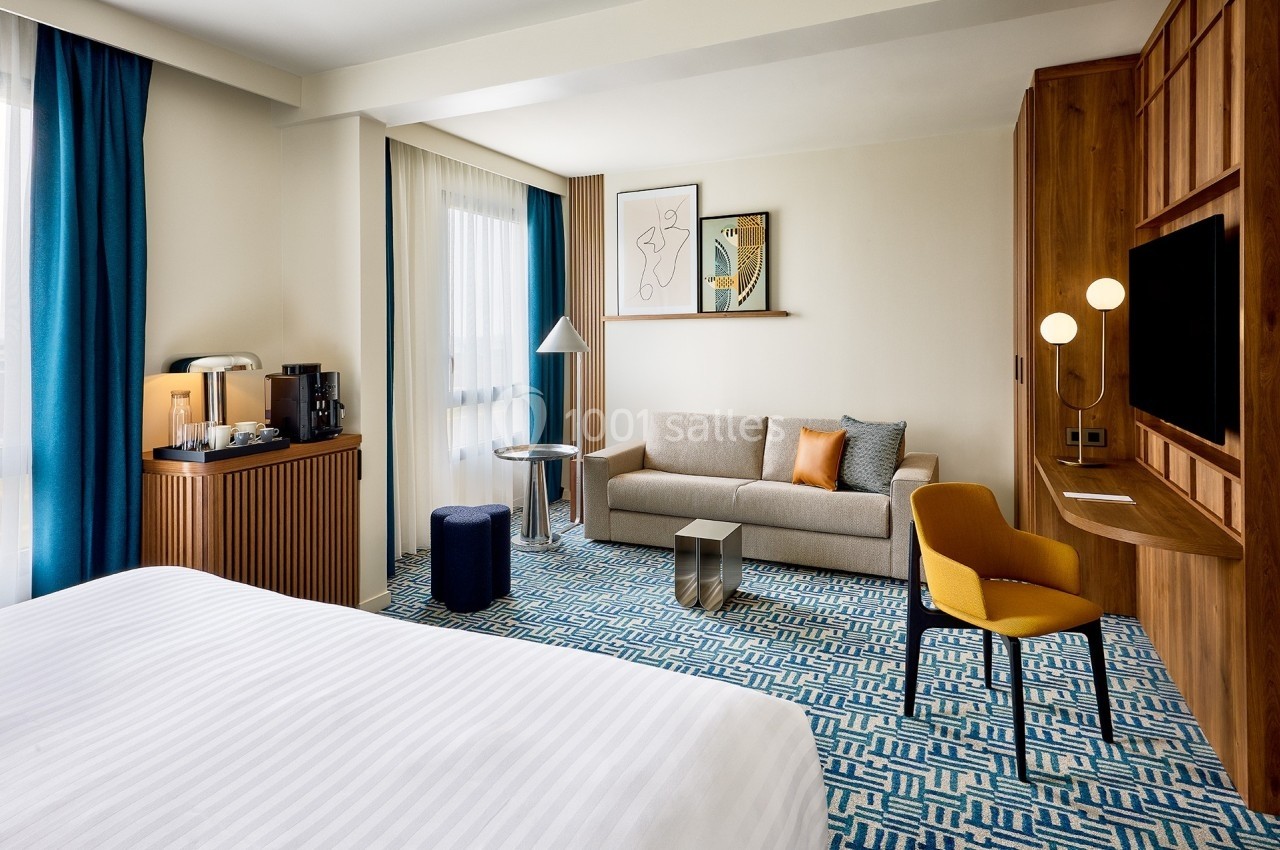 Chambre d'hôtel moderne avec lit, canapé, bureau, éclairage design et décoration contemporaine.