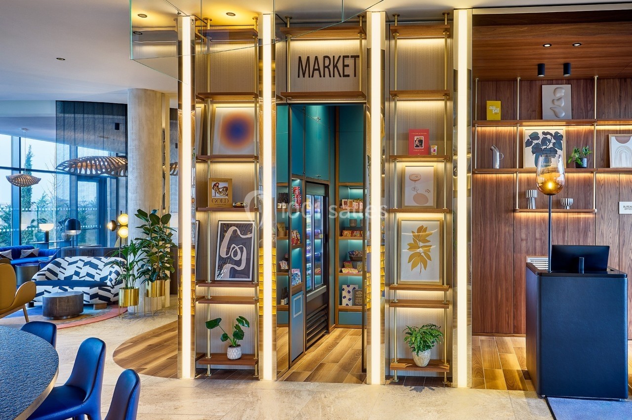 Entrée d'une boutique moderne avec étagères éclairées, œuvres d'art encadrées et présentoirs de produits colorés.
