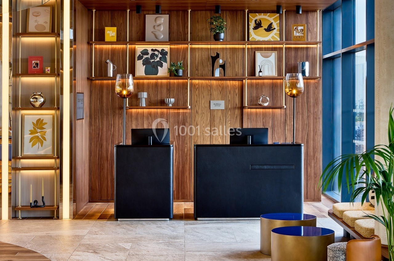 Comptoirs d'accueil modernes devant une étagère en bois décorée d'objets et d'œuvres d'art, dans un espace lumineux.