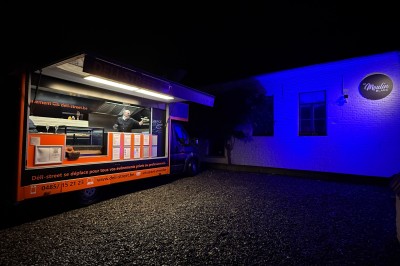Miniature Location salle Braine-l'Alleud (Brabant wallon) - Le Moulin Blanc #15 Camion de restauration éclairé la nuit, stationné devant un bâtiment illuminé par une lumière bleue.