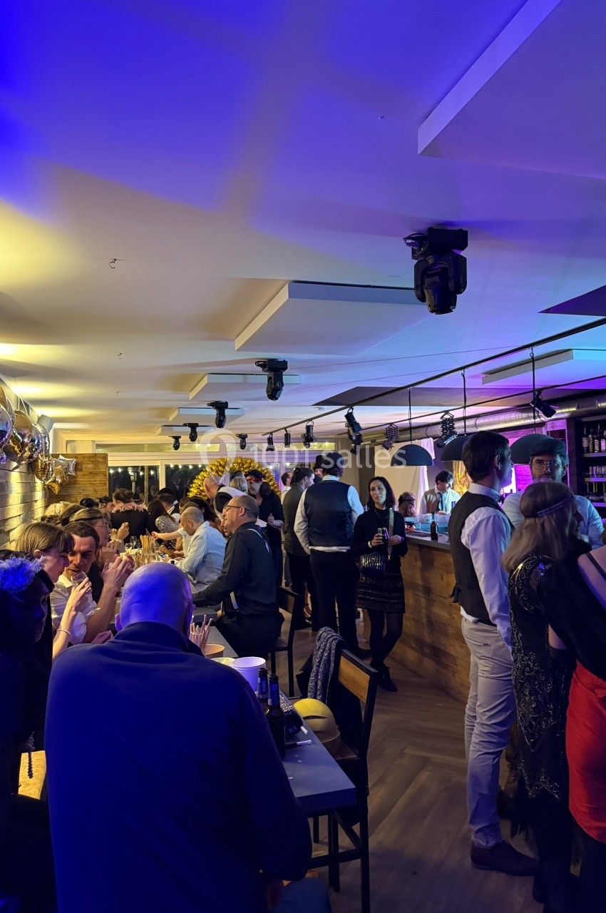 Personnes discutant et partageant un moment convivial dans un bar animé avec éclairage coloré.