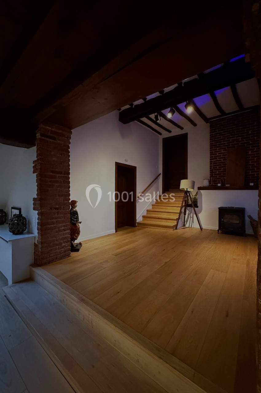 Intérieur d'une maison avec sol en bois, murs en briques, escalier, poêle à bois et décoration sobre.