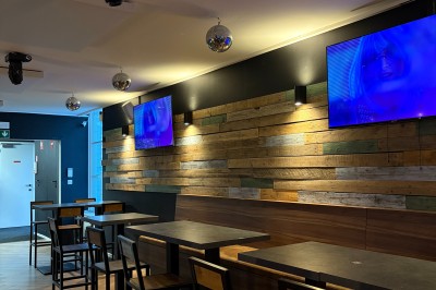 Miniature Location salle Braine-l'Alleud (Brabant wallon) - Le Moulin Blanc #10 Salle lumineuse avec parquet clair, table et chaises au centre, escalier blanc, machine à coudre ancienne et tableau au mur.