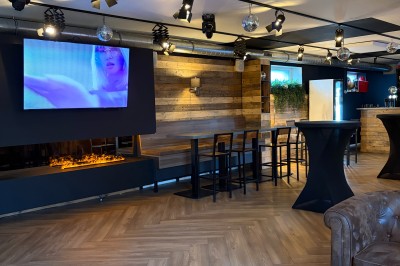 Miniature Location salle Braine-l'Alleud (Brabant wallon) - Le Moulin Blanc #18 Salle lumineuse avec parquet clair, table et chaises au centre, escalier blanc, machine à coudre ancienne et tableau au mur.